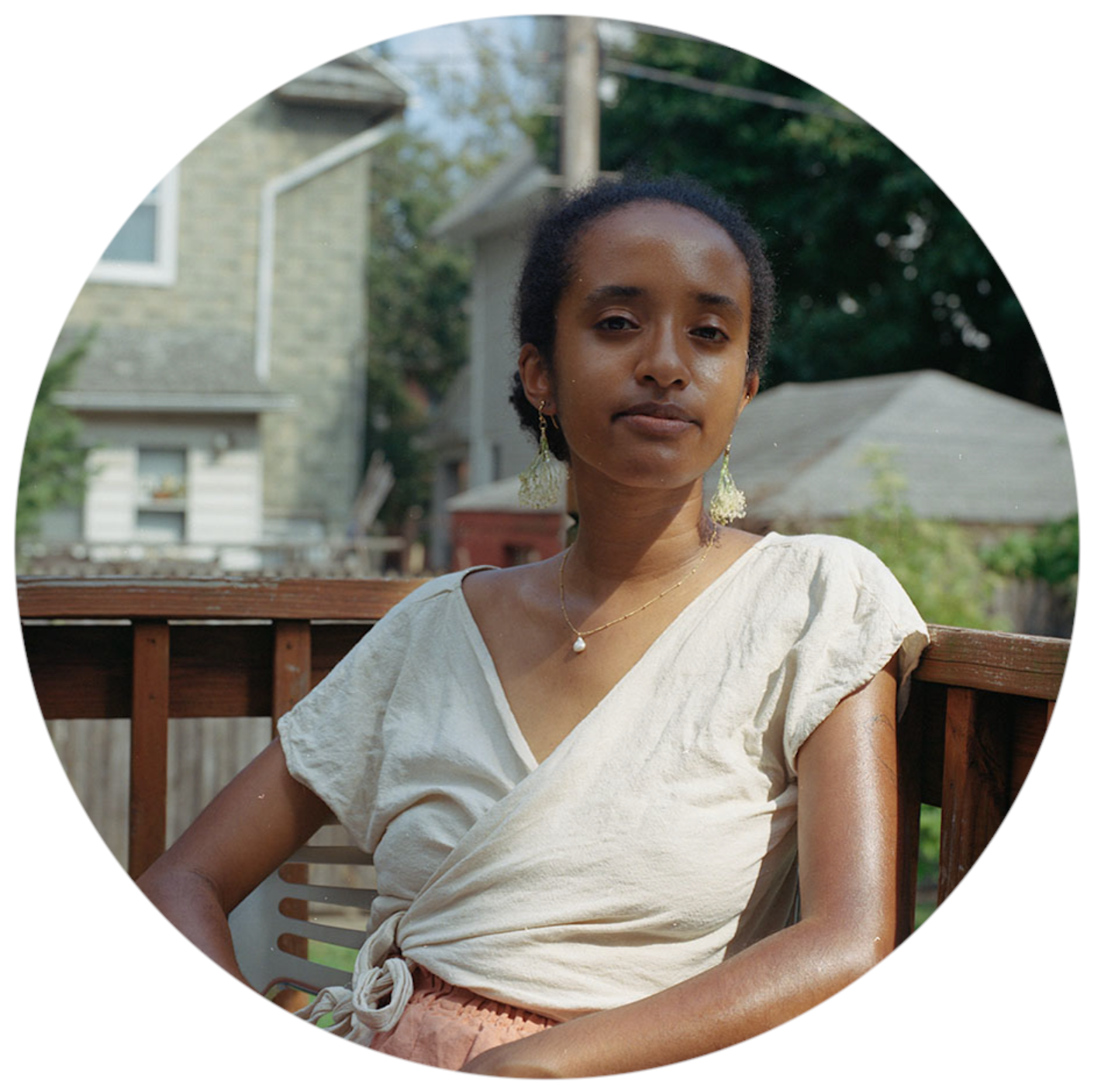 photo of a person with black hair wearing a white wrap shirt sitting on a deck