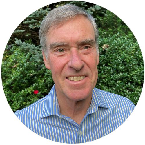 Headshot of a grey-haired man wearing a blue dress